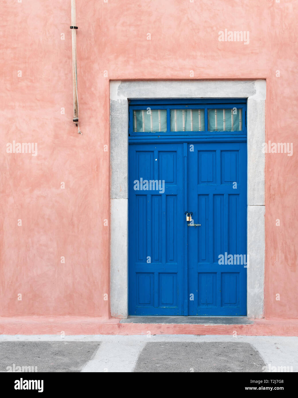 A cobalt blue door against a pink wall on the Greek island of Santorini. Stock Photo
