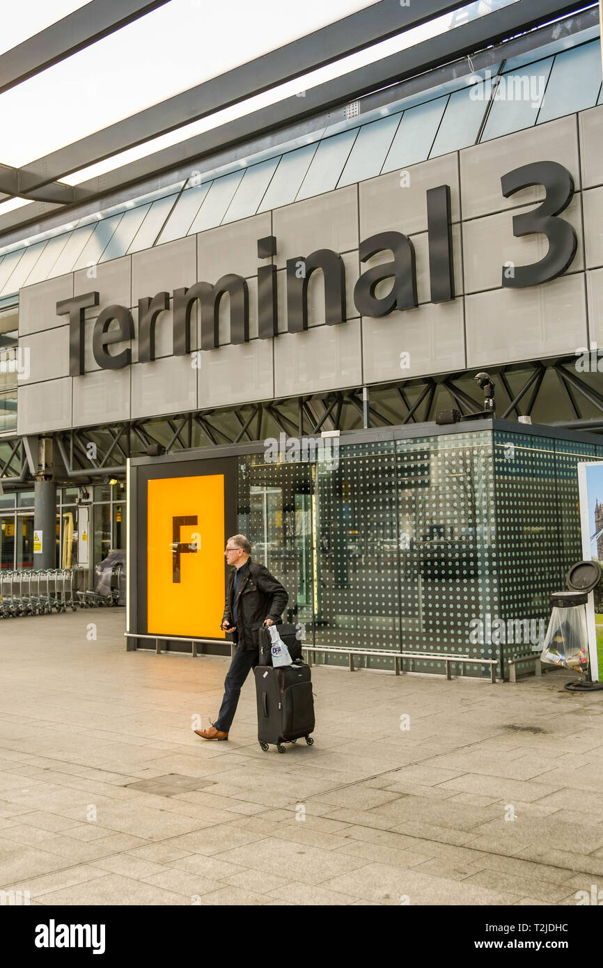 Wheeling his luggage after arriving at heathrow airport in london hi