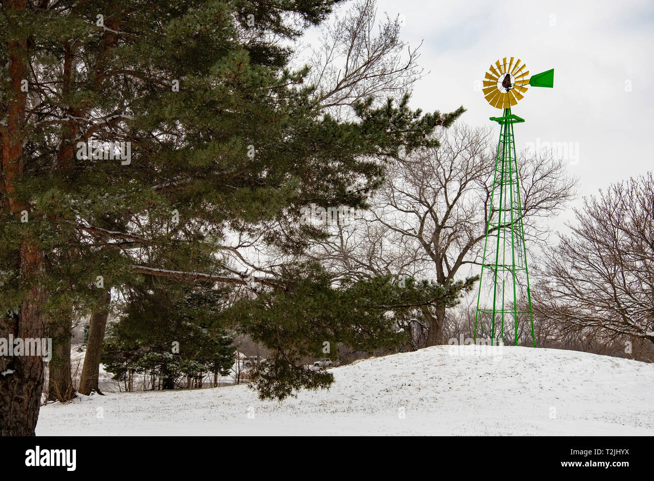 Windmill, painted yellow and green, in Sedgwick county park after a late winter snow. Wichita, Kansas, USA Stock Photo