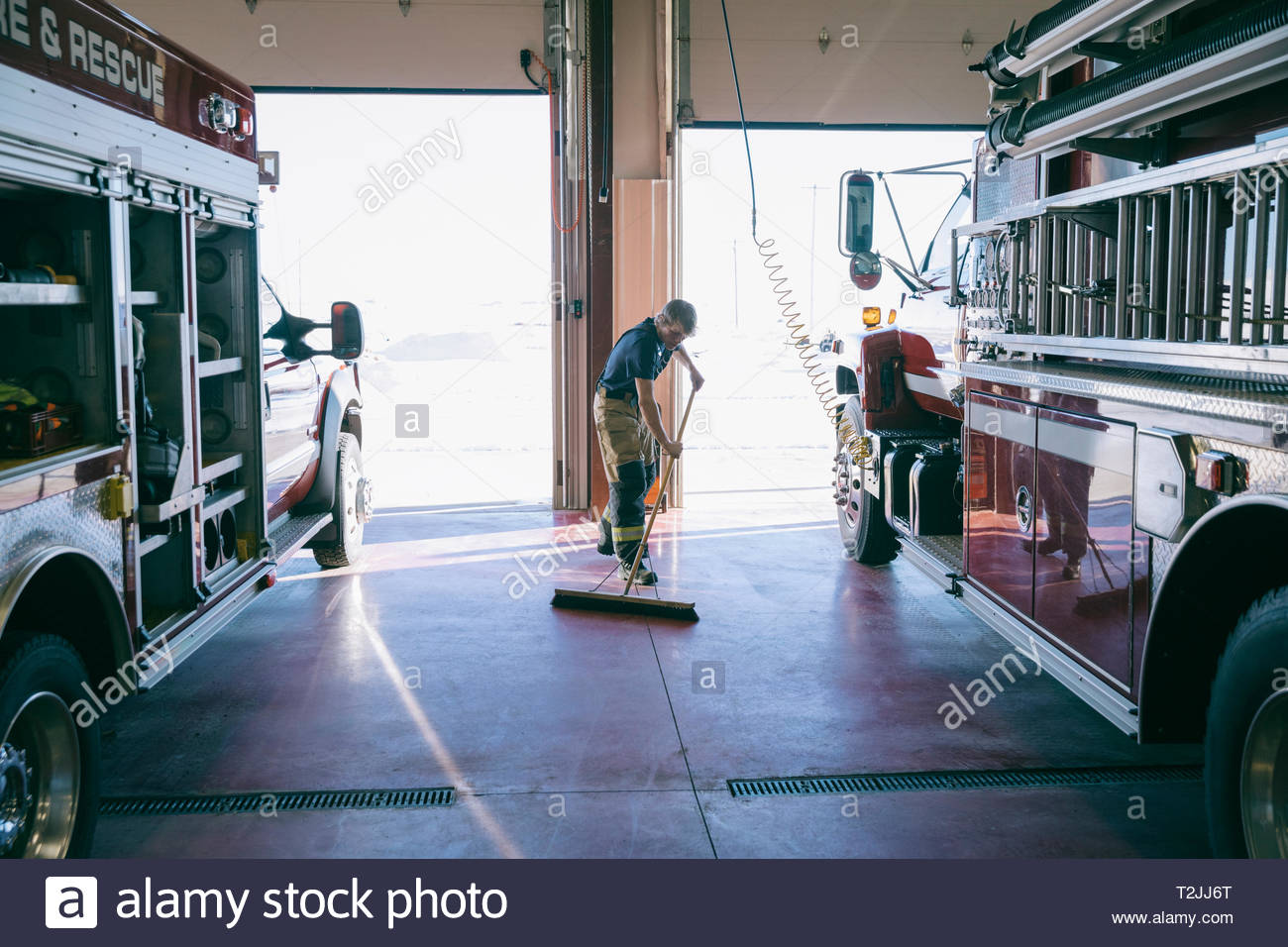 Firefighter sweeping fire station floor Stock Photo Alamy