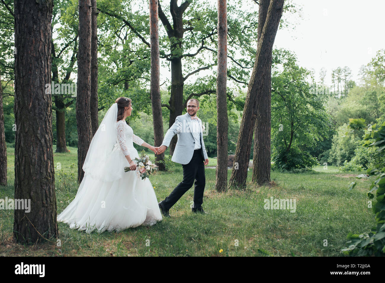 Bride and groom are walking in the woods on their wedding day Stock ...