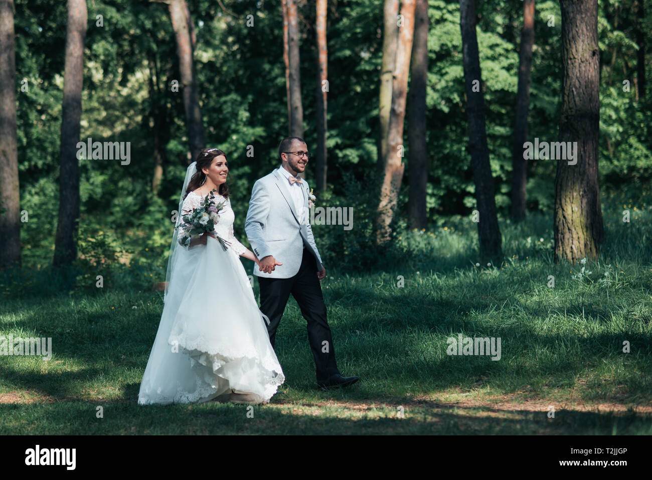 Bride and groom are walking in the woods on their wedding day Stock ...
