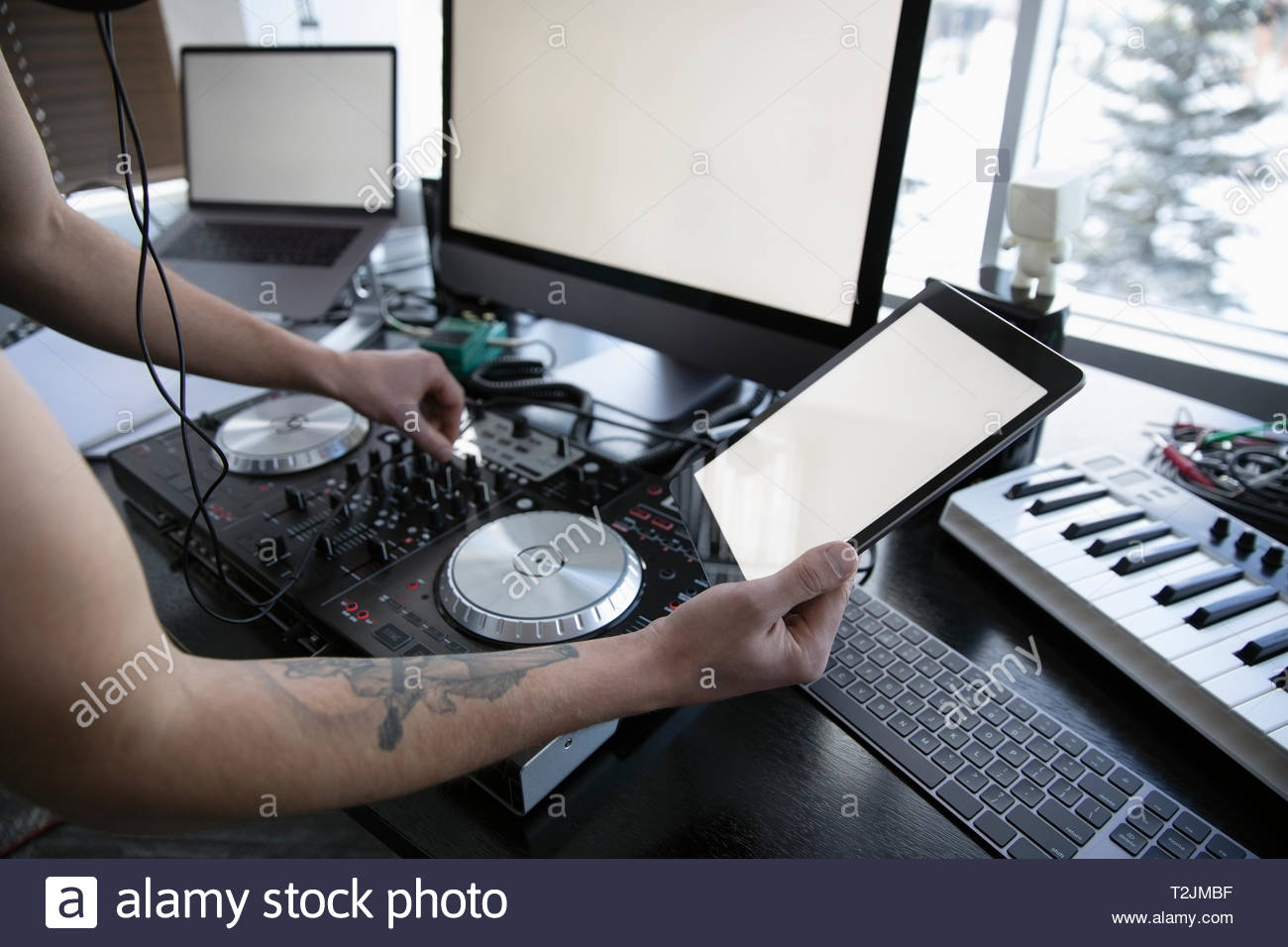 DJ with digital tablet using digital mixing tables at desk Stock Photo