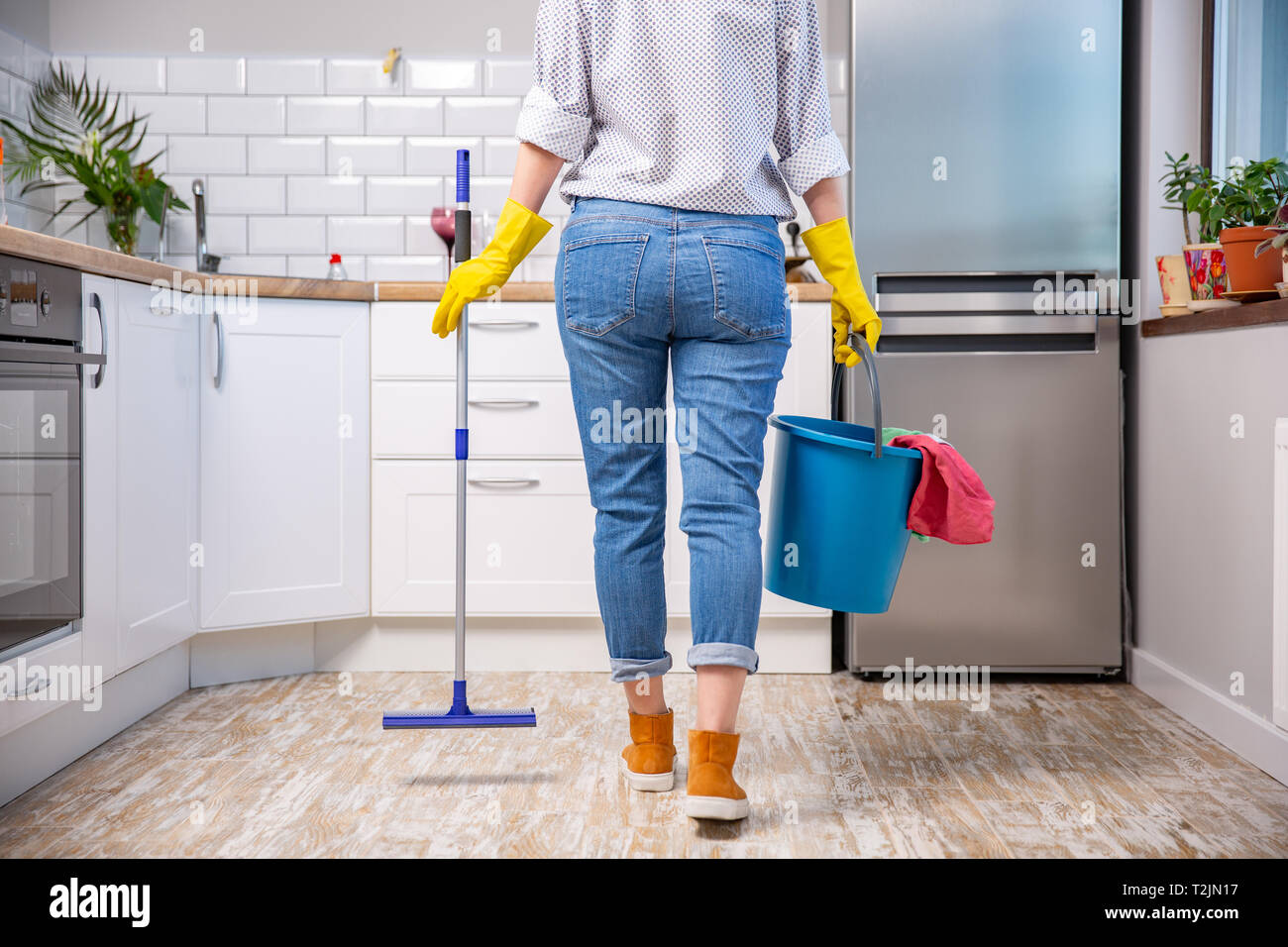 Woman holding mop and bucket with cleaning agents at home. cleaning the