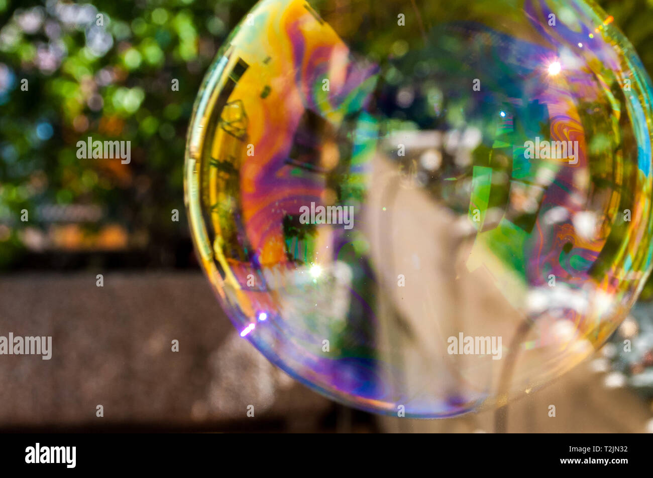 kids big rainbow colored soap bubble floating in garden Stock Photo