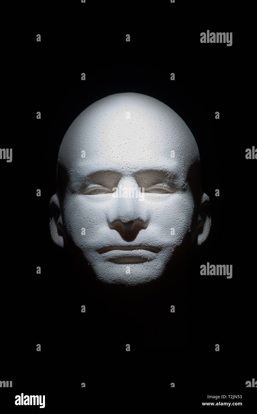 floating white mannequin head with black background lighted from above Stock Photo