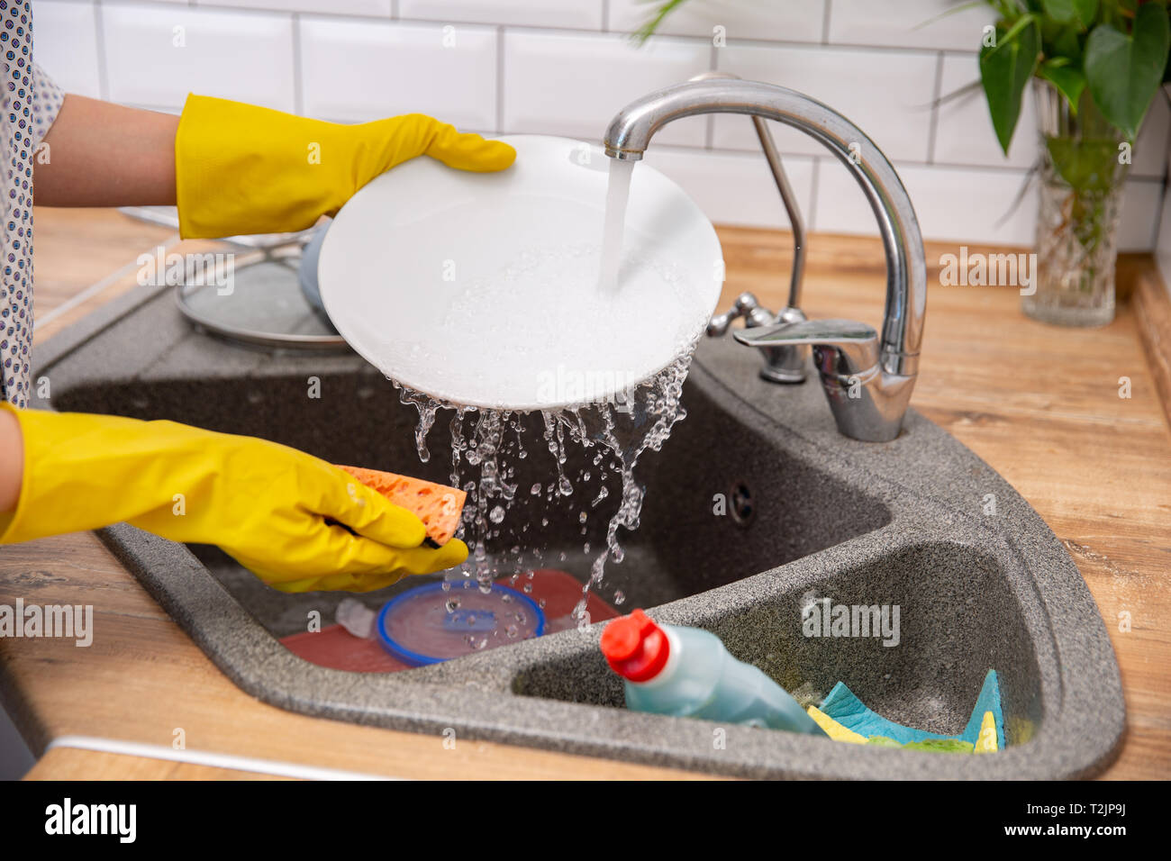 Close up hands wearimg at rubber gloves washing dishes in kitchen Stock