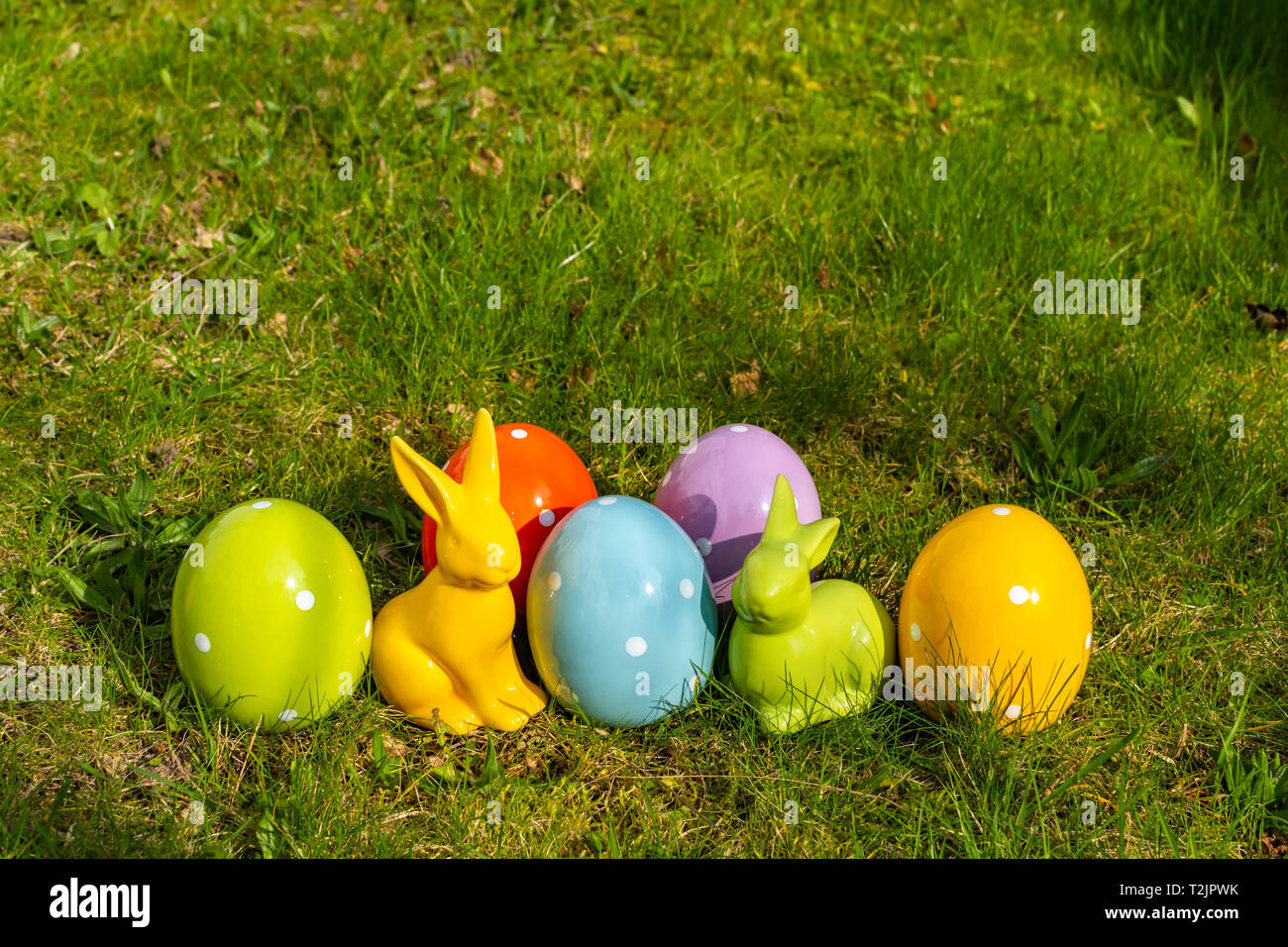 Colorful ceramic easter eggs and Easter bunnies on a meadow. Stock Photo
