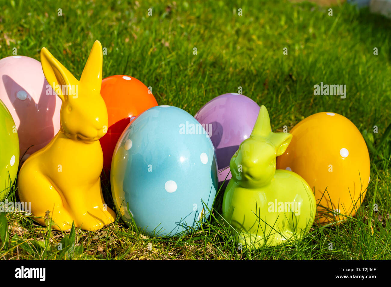 Colorful ceramic easter eggs and Easter bunnies on a meadow. Stock Photo