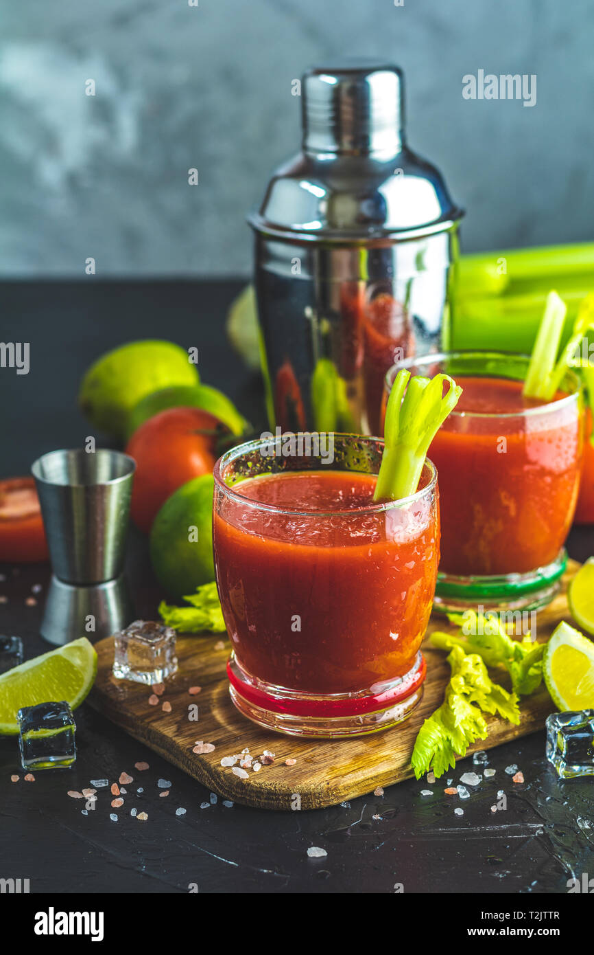 Tomato juice with celery, spices, salt and ice in portion glasses with