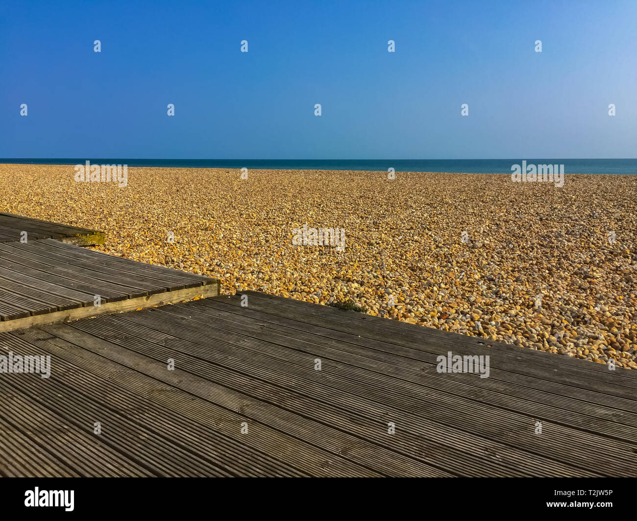 Shingle beach against the calm sea and a clear blue sky Stock Photo