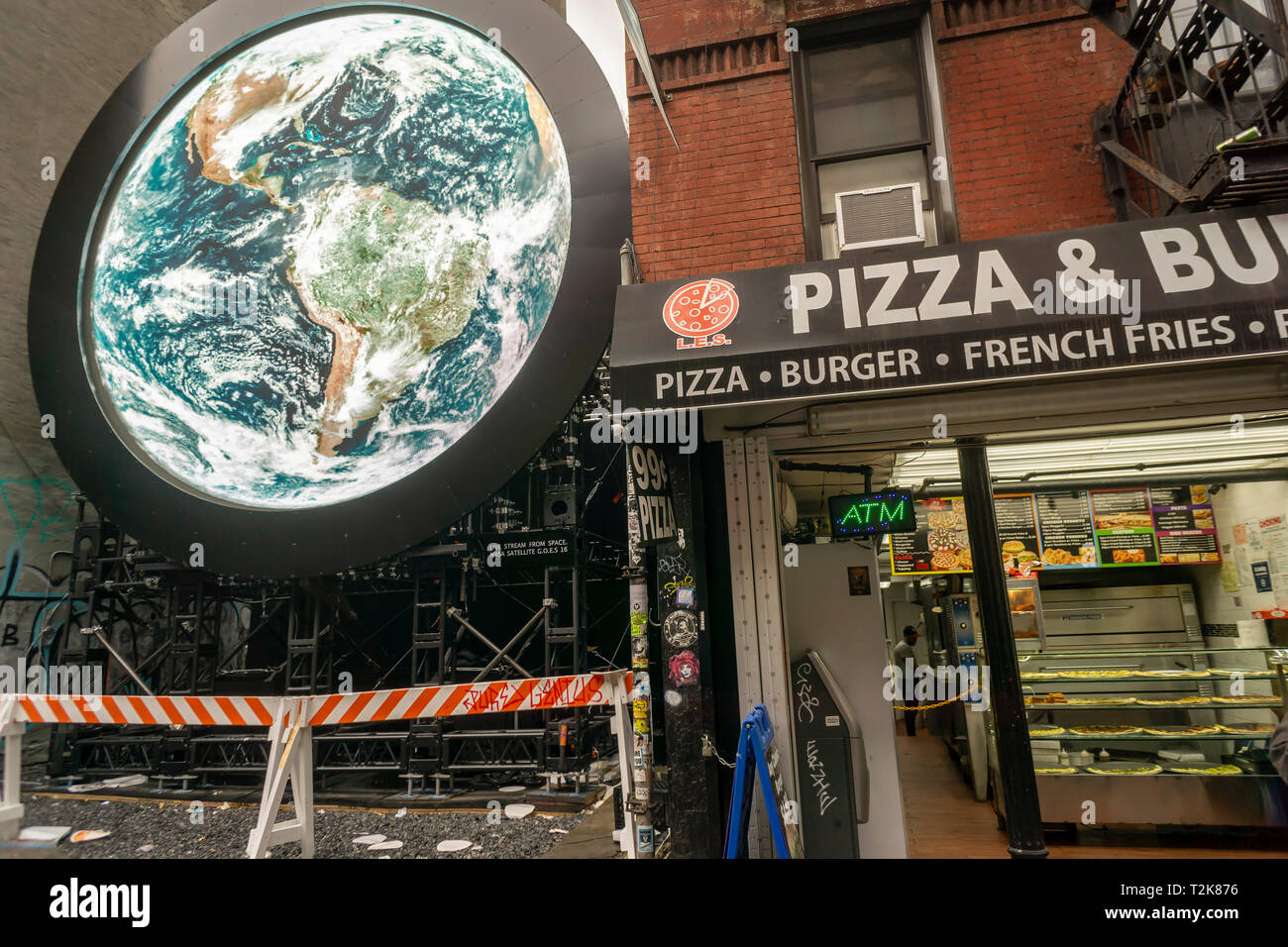 Visitors pass a livestream view of the planet Earth taken from a  NASA satellite is projected on an installation entitled 'blu Marble' on Ludlow Street in the Lower East Side neighborhood of New York on Sunday, March 31, 2019. The work by artist Sebastian Errazuriz is sponsored by the vaping company blu as part of their charitable 'Pledge World by blu' campaign. (© Richard B. Levine) Stock Photo