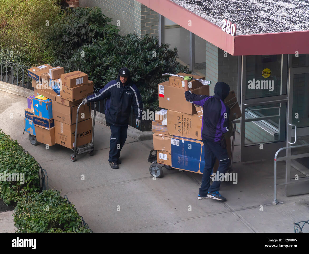 A duo of deliverymen from FedEx with their carts laden with purchases