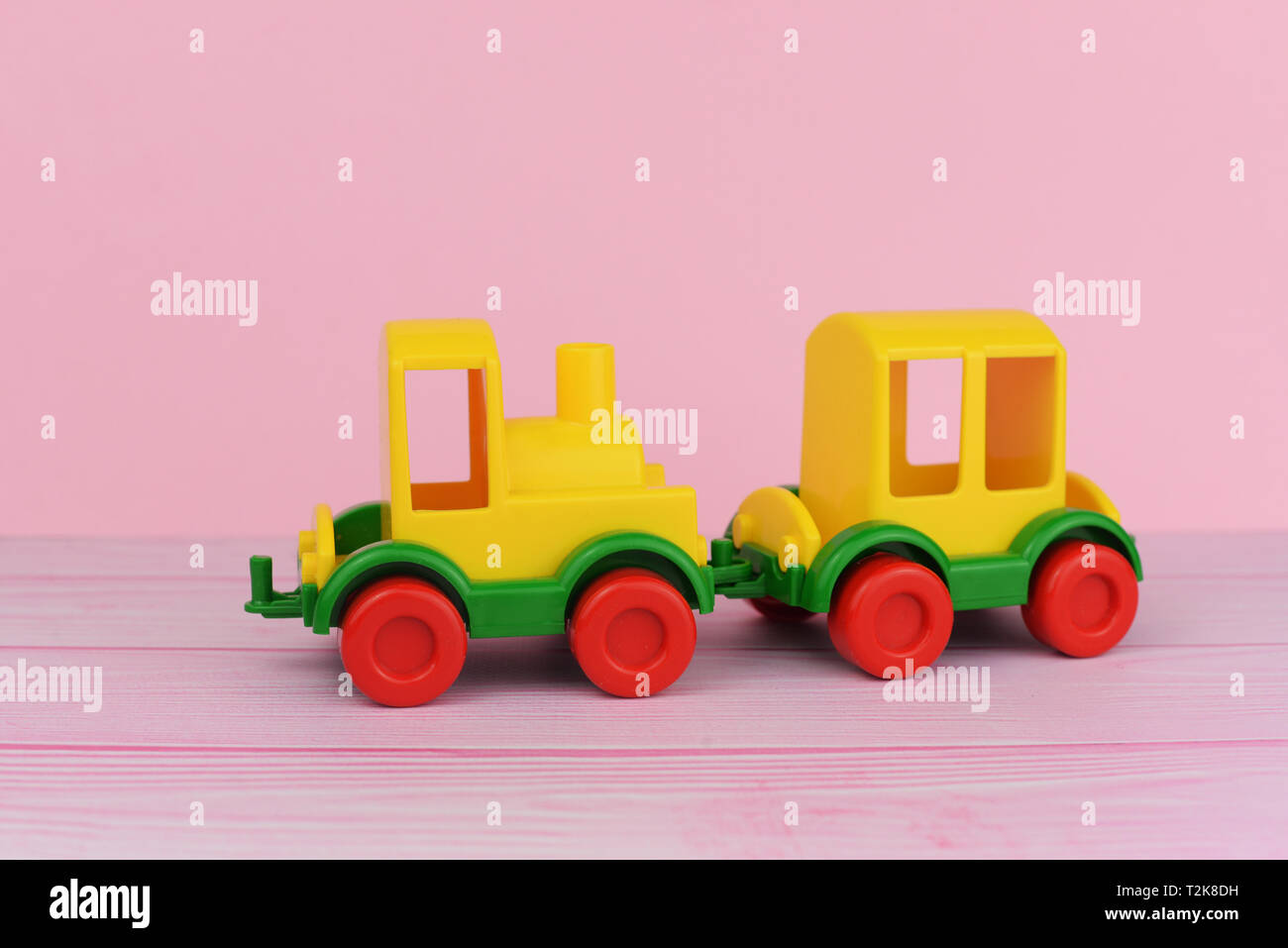 children's toy train for playing with cars yellow on a pink background Stock Photo