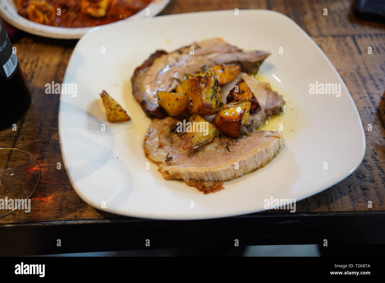 Plate of sliced italian suckling pig with roast herb potatoes Stock