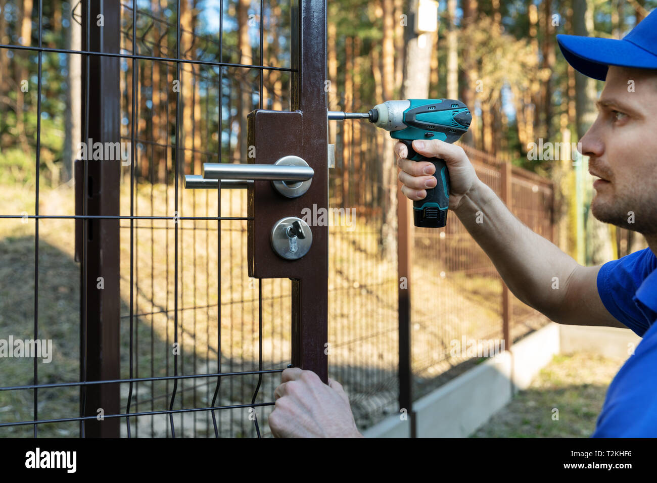 worker installing the lock for new metal fence gates Stock Photo