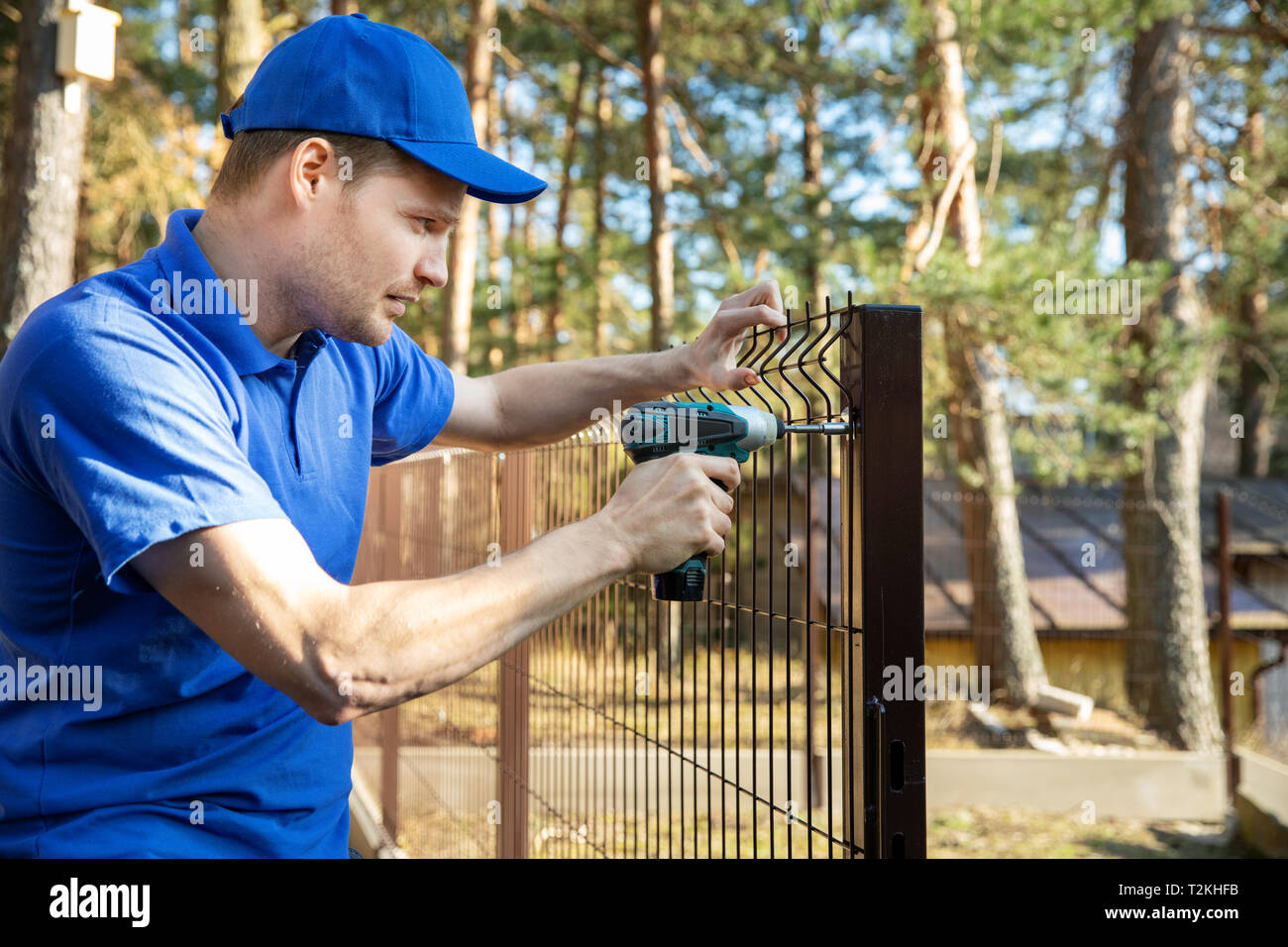 fencing services - worker installing welded metal mesh fence Stock Photo