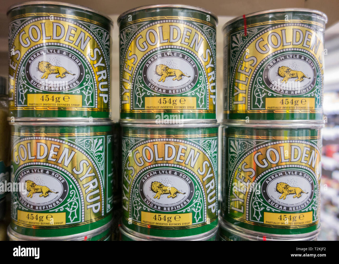 Tins of Lyle's Golden Syrup tins stacked on a supermarket shelf in
