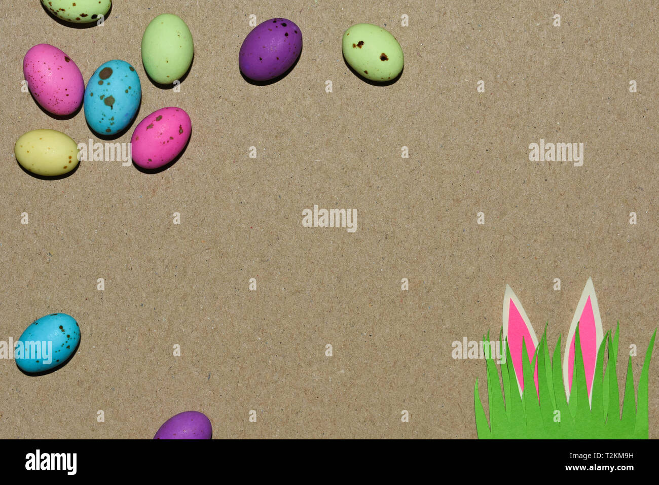 Speckled Eggs With Grass Patch And Rabbit Ears On Natural Cardboard Stock Photo