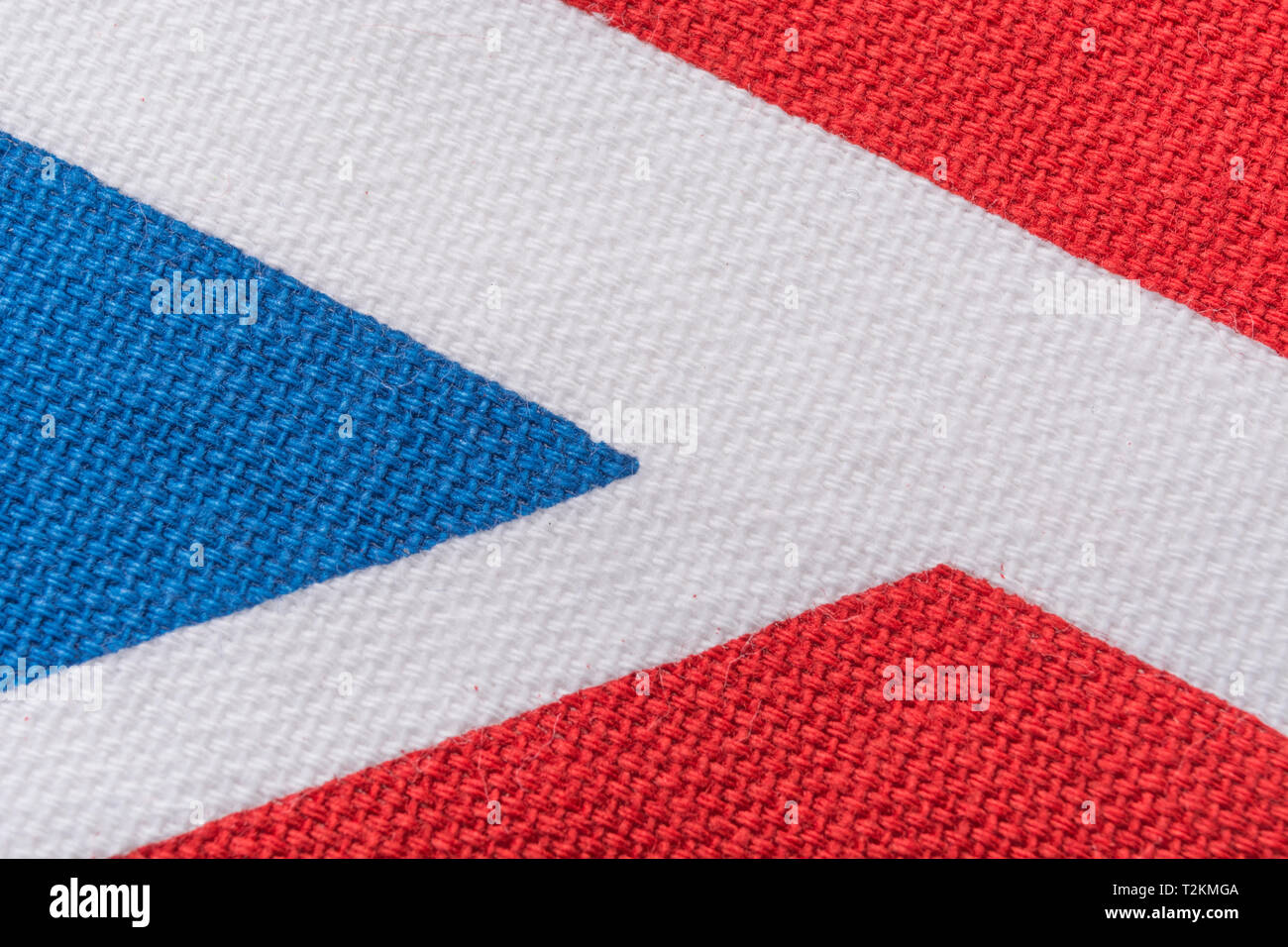Close-up macro of Union Jack printed cotton material, showing colourful threads, warp and weft pattern, regular rows of stitches, Union Jack abstract. Stock Photo