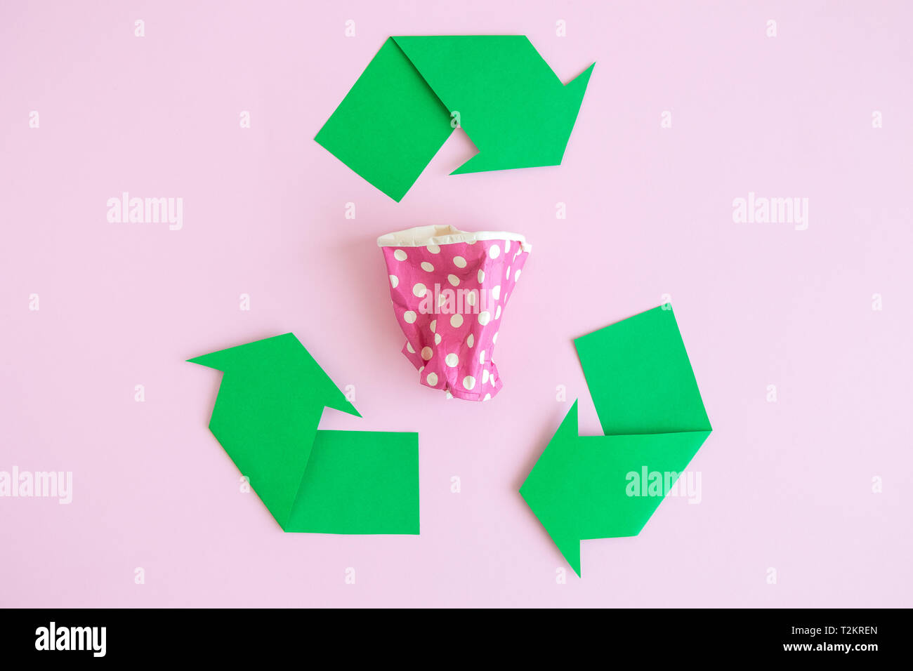Disposable paper cup with recycling sign against pastel pink background ...
