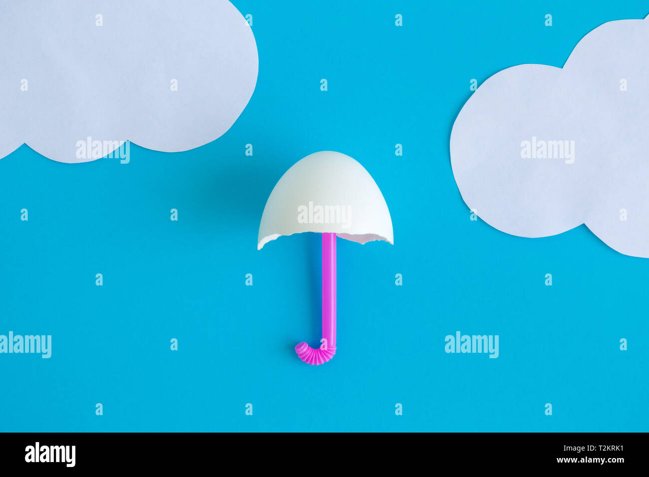 Flat lay of umbrella made of egg shell and drinking straw with paper