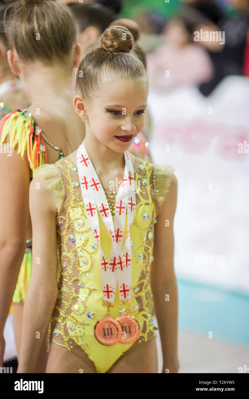 Little gymnast with her sports awards on the carpet in rhythmic