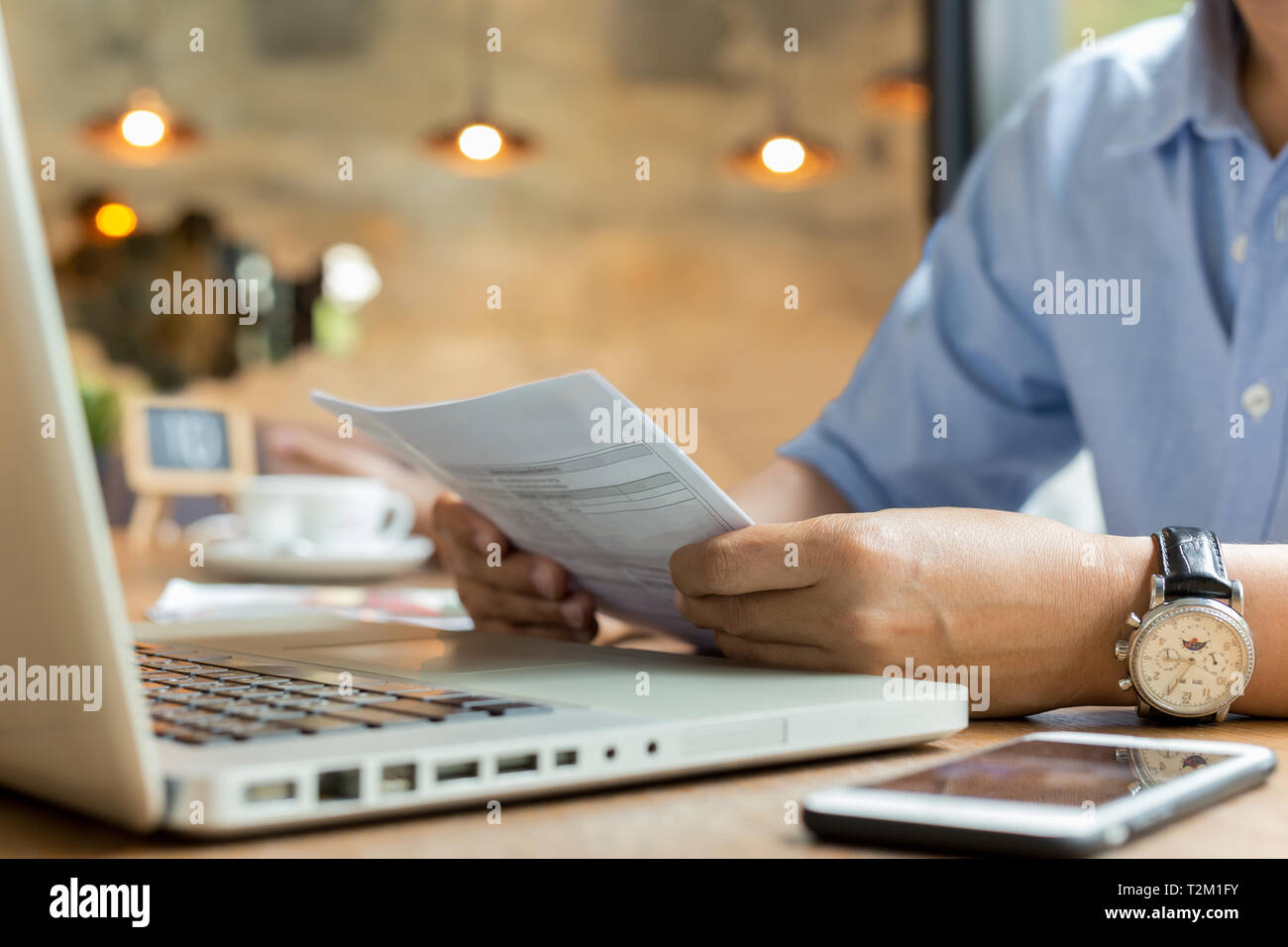 Businessman using laptop while looking at invoice Stock Photo
