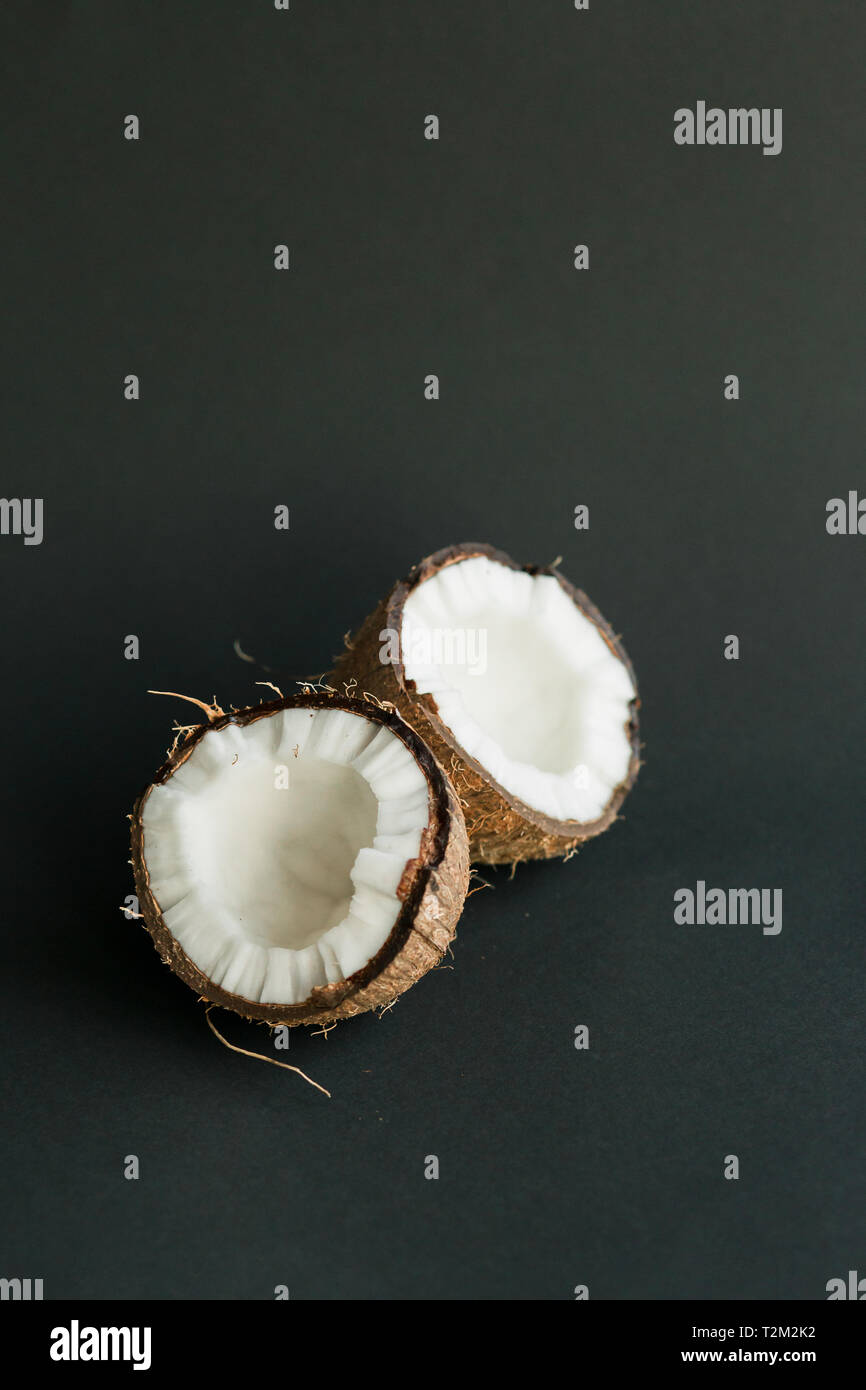 Broken ripe coconut on black background. brown peel and white flesh ...