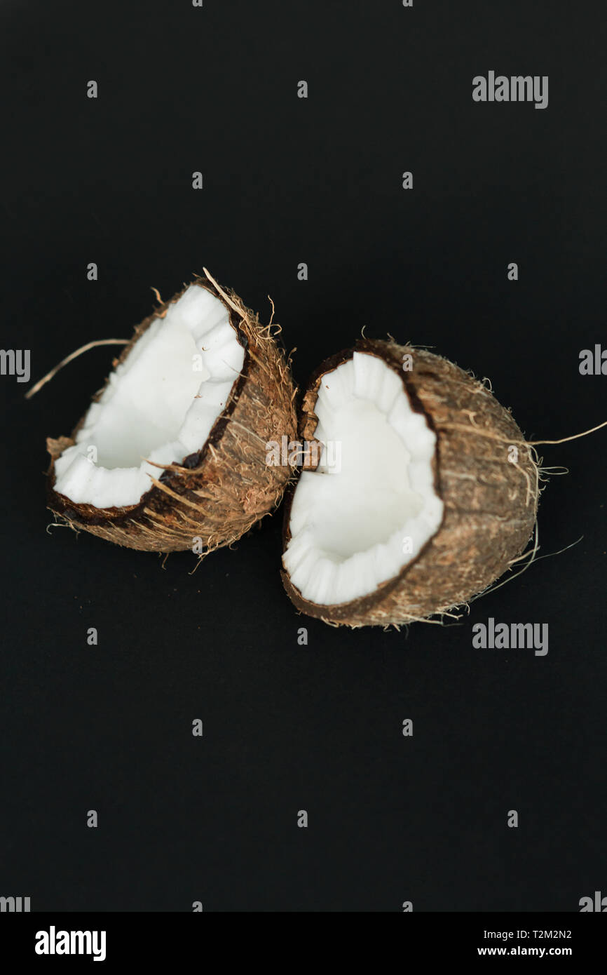 Broken ripe coconut on black background. brown peel and white flesh ...