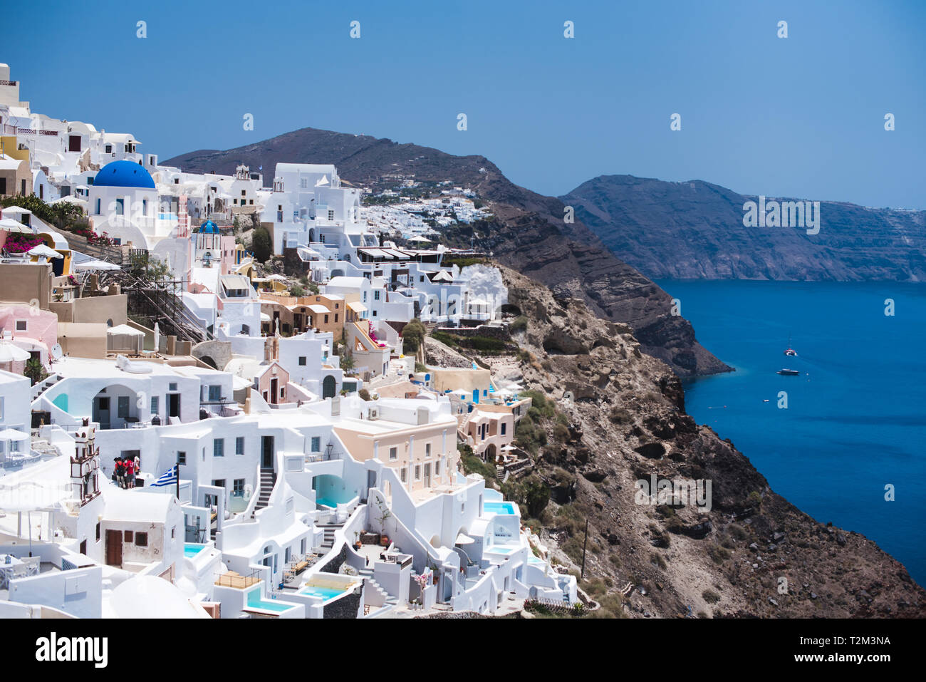 A colorful Greek village sits on a cliff-side in Santorini. Stock Photo