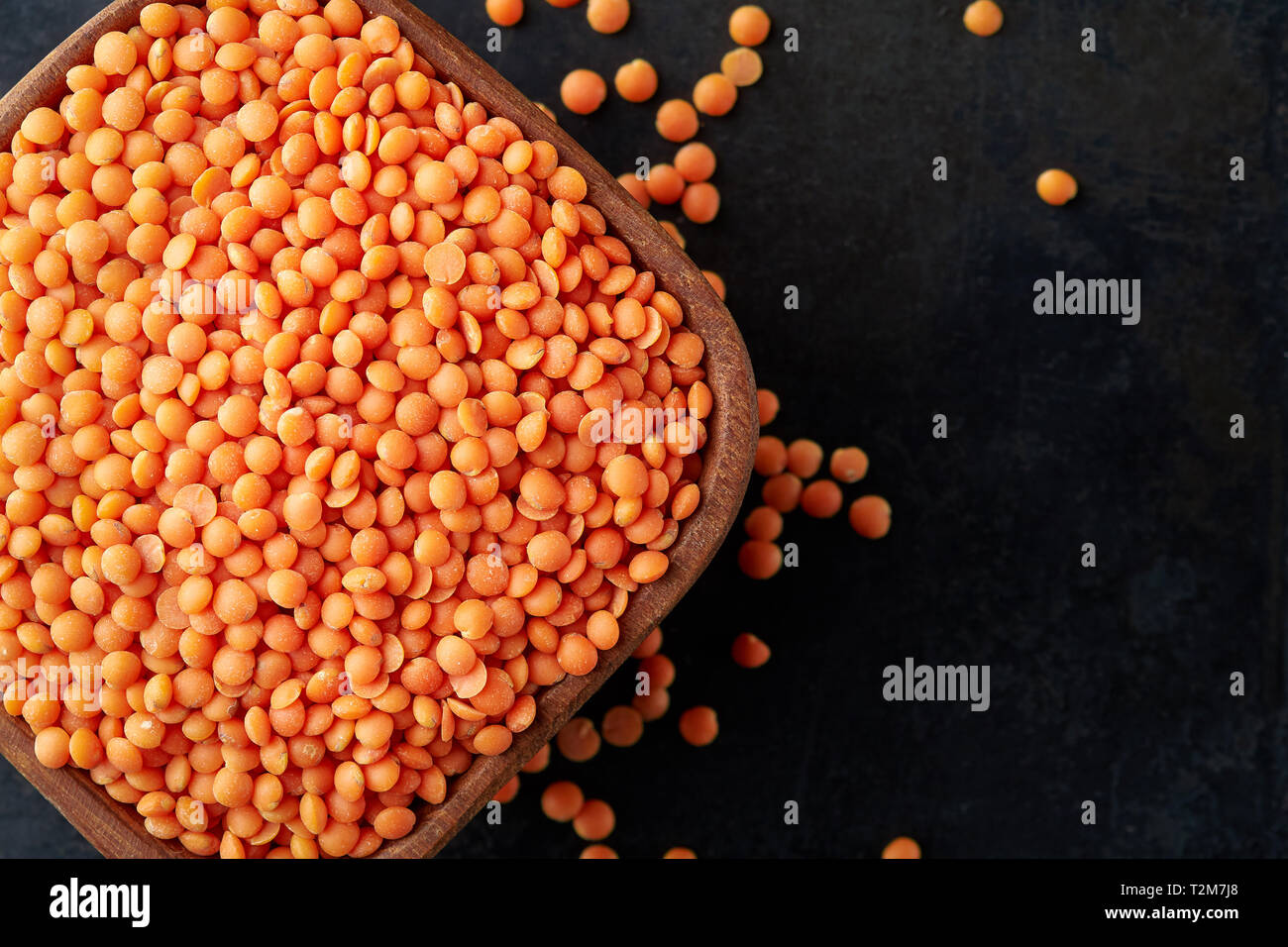 Raw uncooked red lentils (lens culinaris) in wooden bowl. Top view with ...