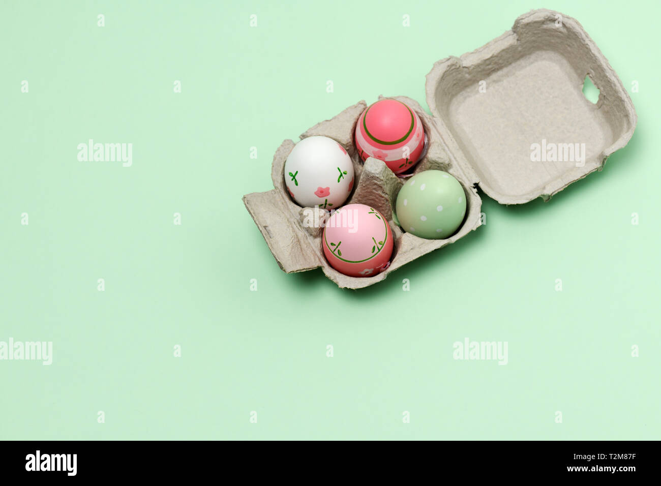 paper container with decorated easter eggs on a green background Stock Photo