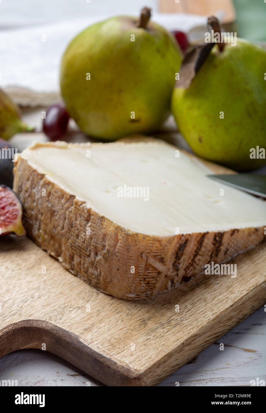 Piece of French cheese Tomme de Brebis made from sheep milk served as dessert with fresh figs and pears close up Stock Photo