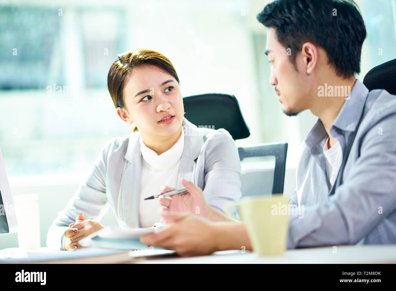 asian businessman and businesswoman working together in office discussing business plan. Stock Photo