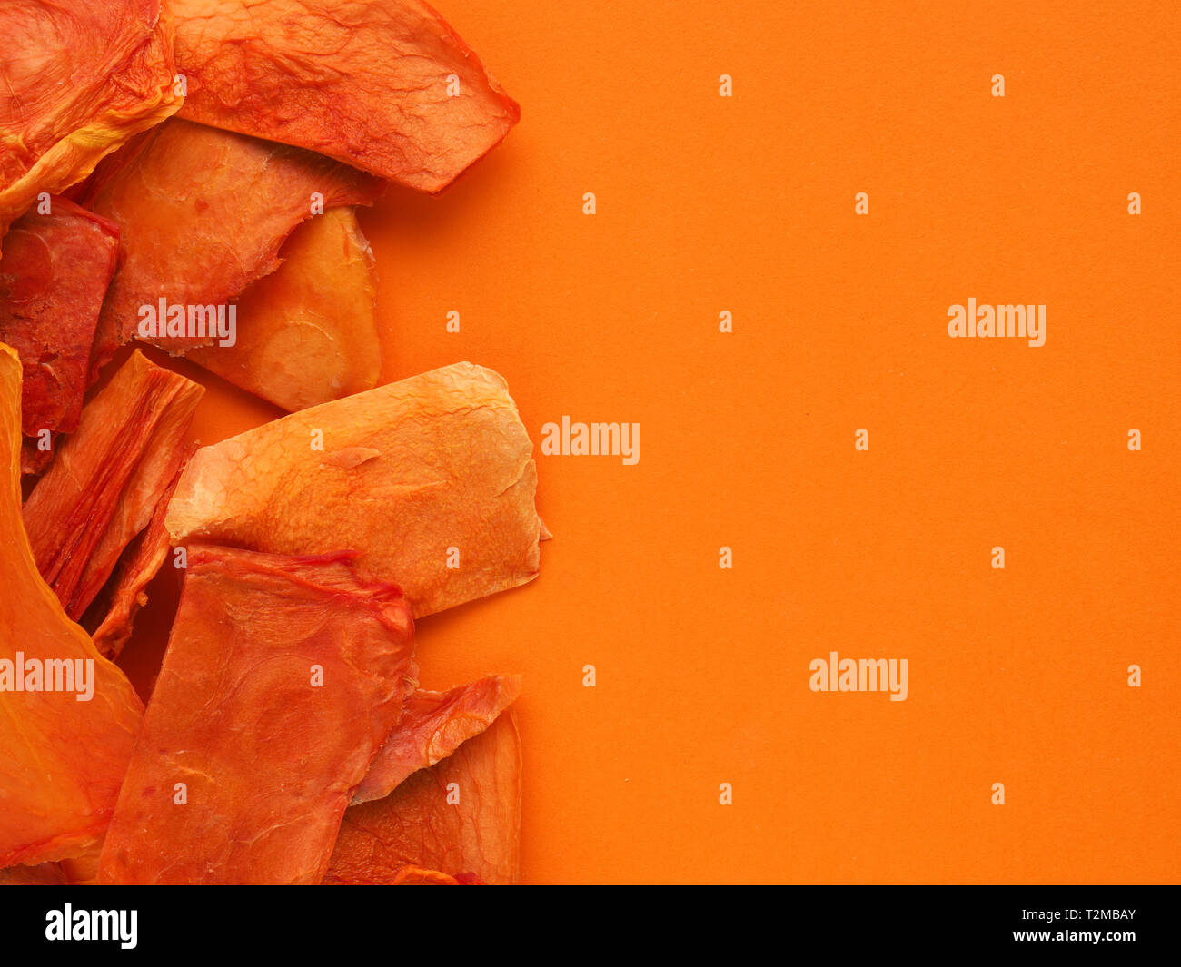 Dried organic papaya slices on an orange studio background, healthy food concept, view from above, space for text Stock Photo
