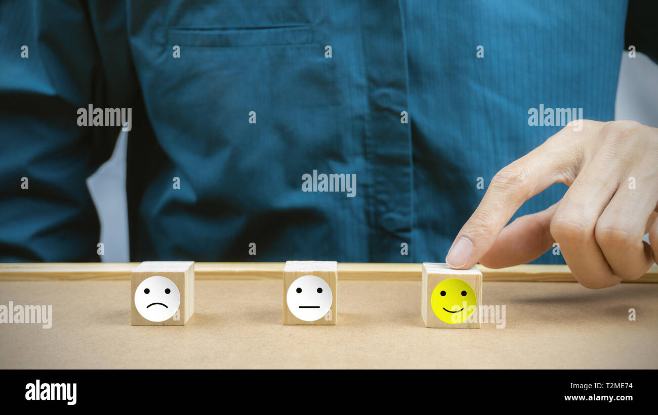 Conceptual the customer responded to the survey. The client using hand choose happy face smile icon on wood block. Depicts that customer is very satis Stock Photo