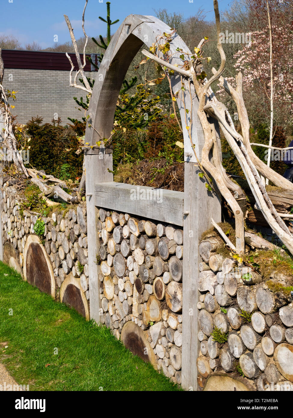 Cut log wall and green oak arch on the front of the Millenium Garden at Buckfast Abbey, Devon, UK Stock Photo