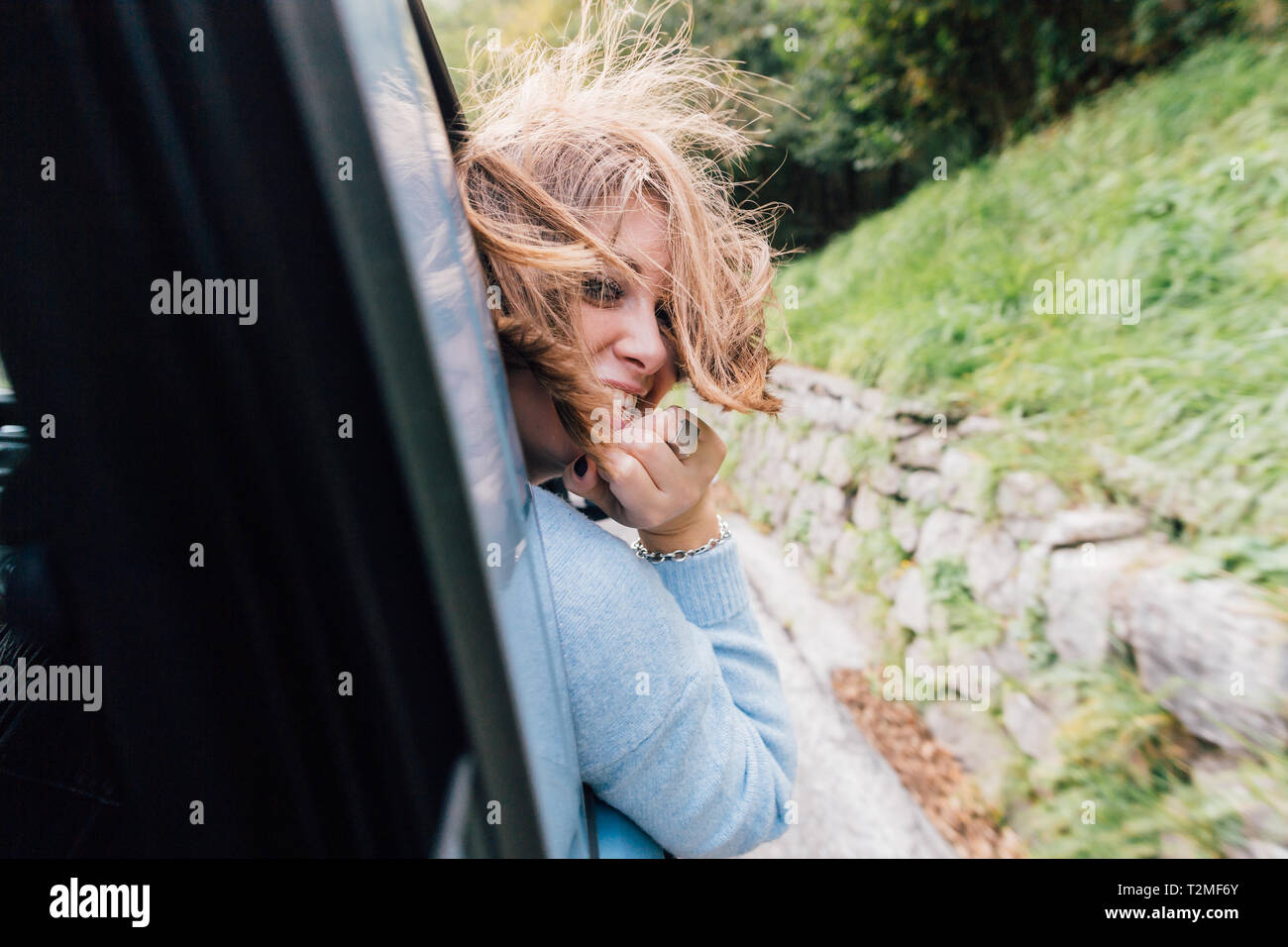 Woman turning around out of car window Stock Photo