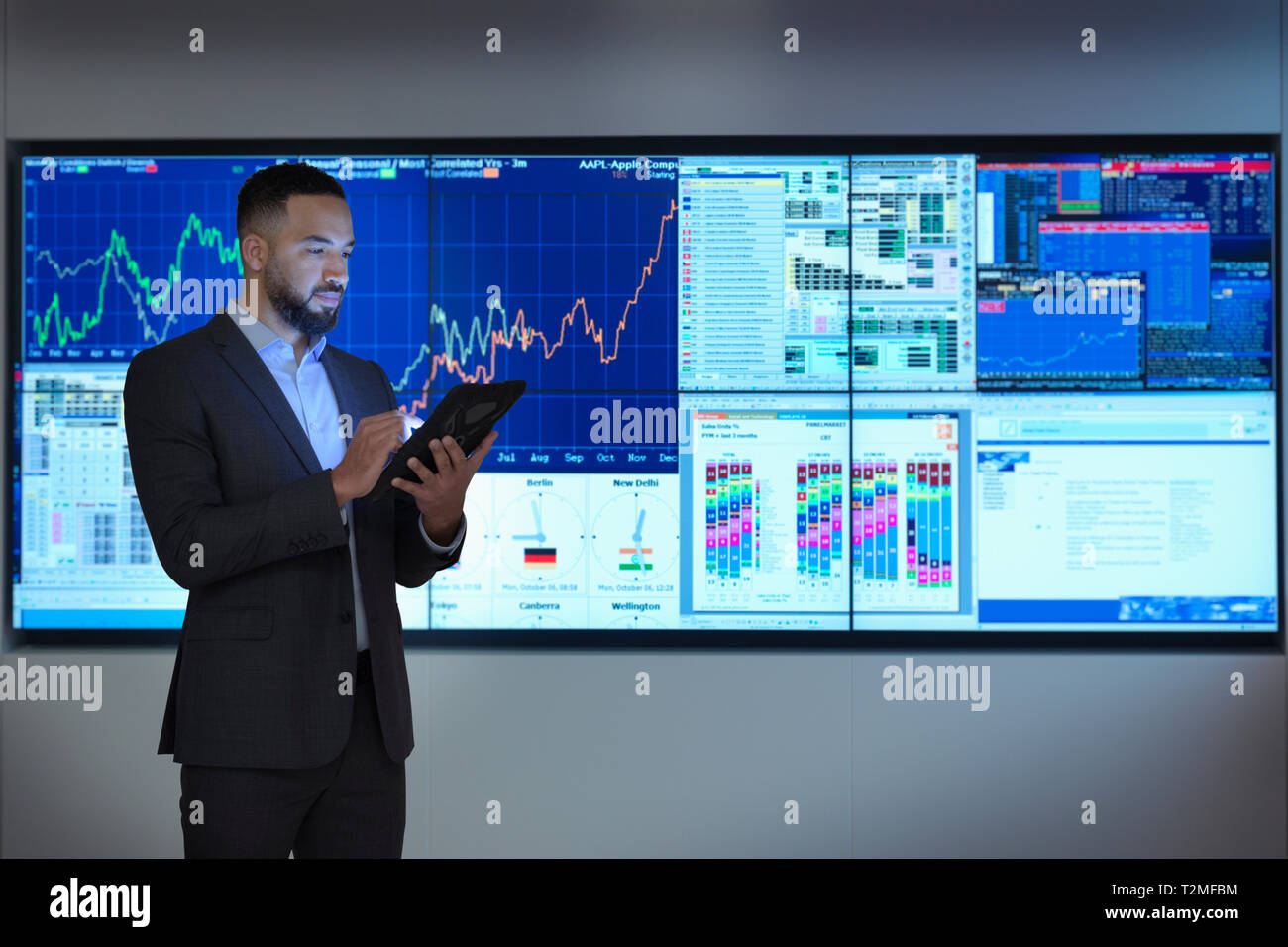 Composite image of businessman using digital tablet in front of digital charts Stock Photo