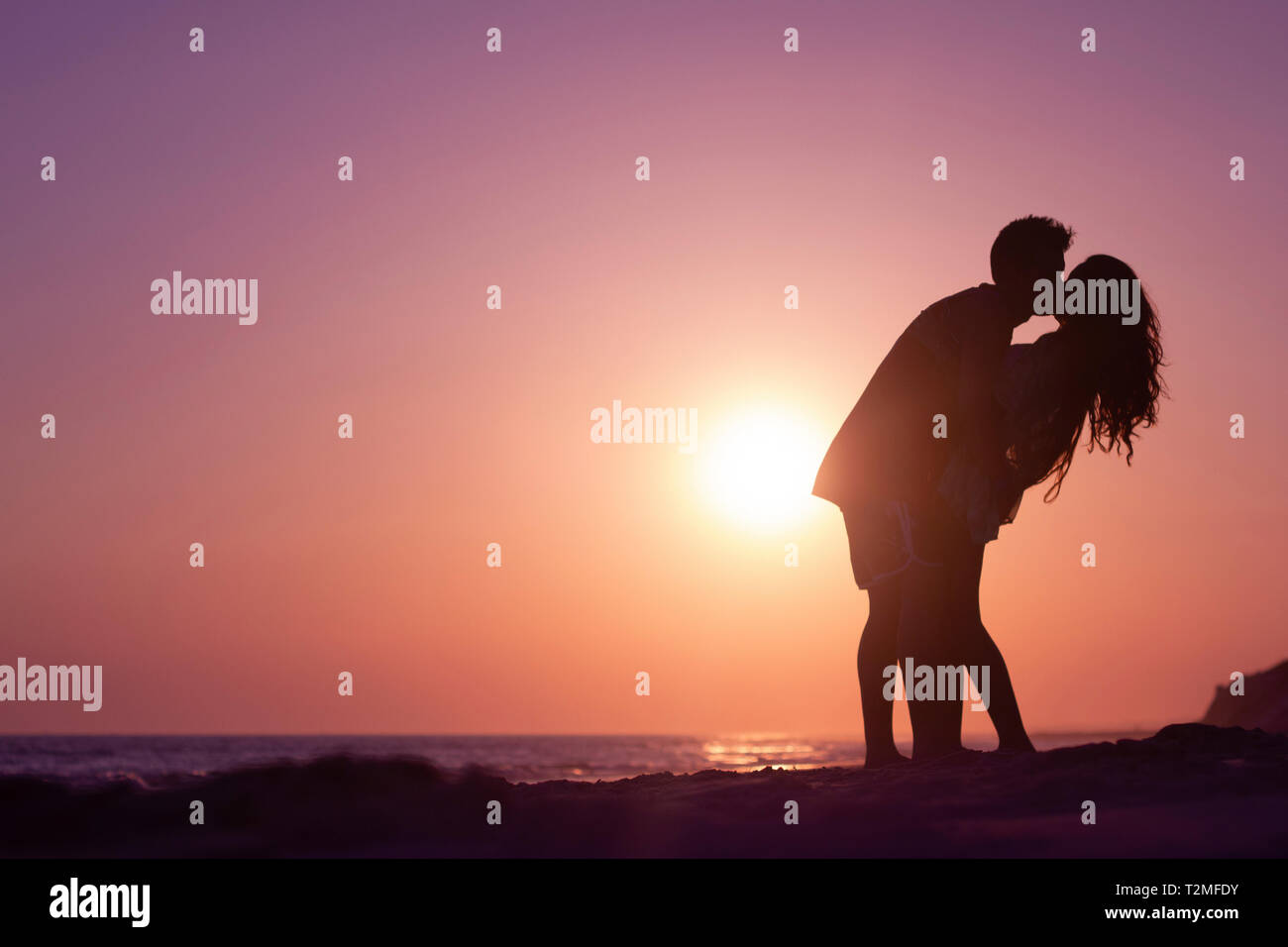 silhouette of a couple kissing on the beach at sunset Stock Photo - Alamy