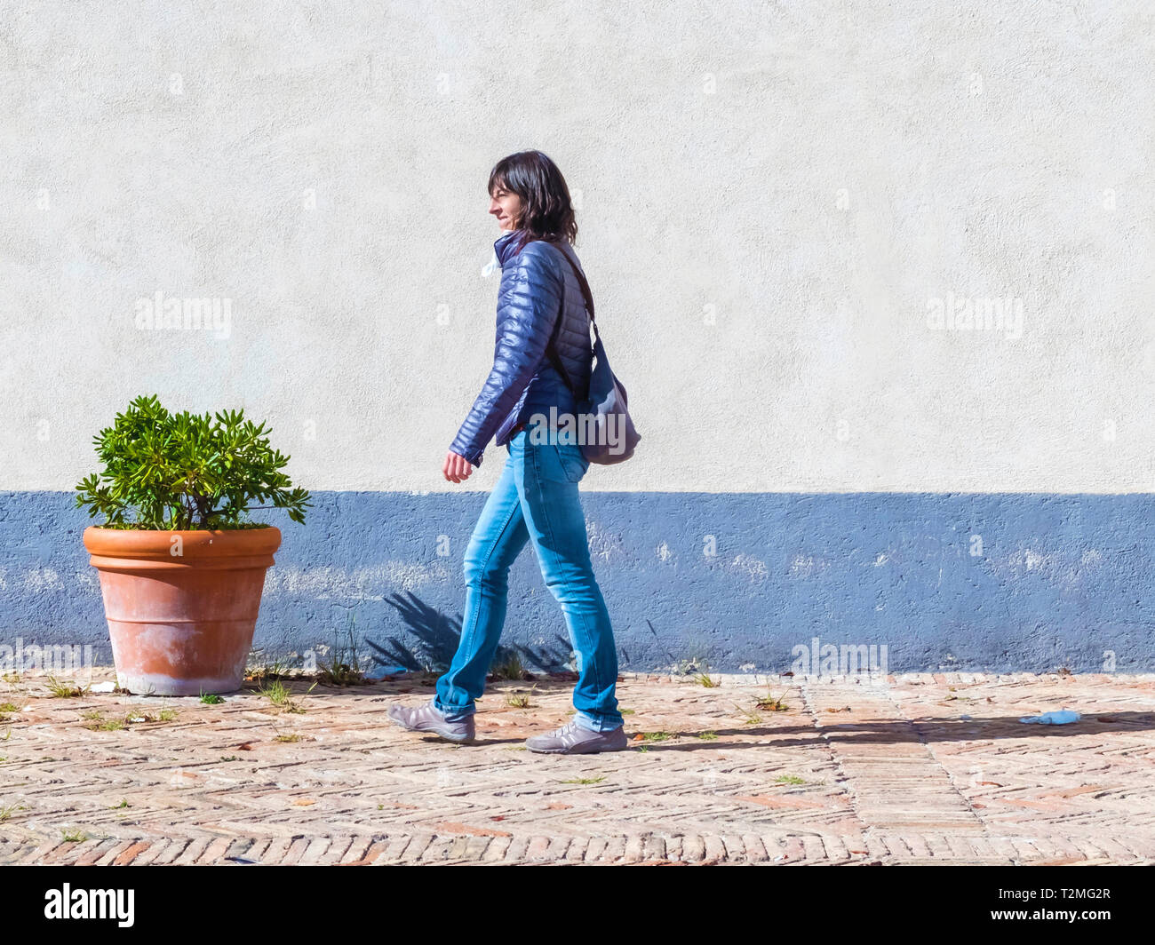 Young woman in blue walking down the street in sunny day Stock Photo