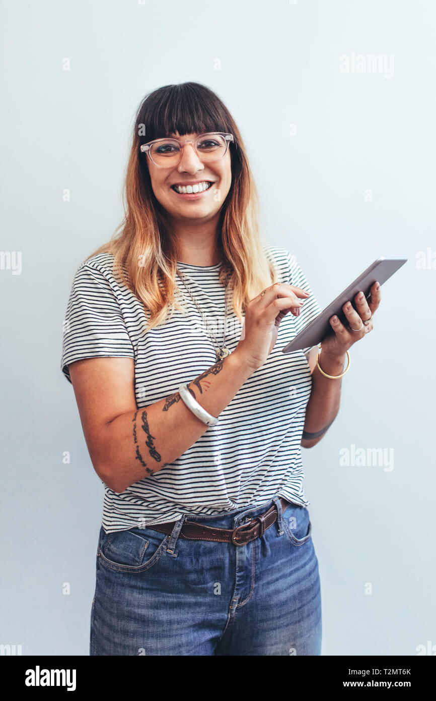 Close up of a smiling businesswoman standing with a tablet pc in hand. Portrait of a cheerful entrepreneur working on a tablet pc in office. Stock Photo