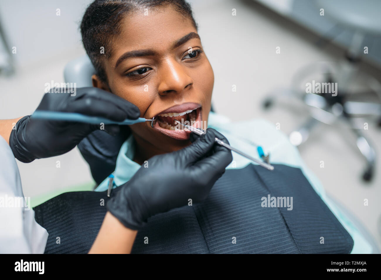 Dentist examines the teeth of female patient in dental clinic. 