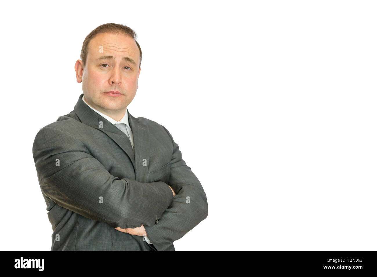 A perplexed-looking, stern businessman with crossed arms on a white background with copy space. Stock Photo