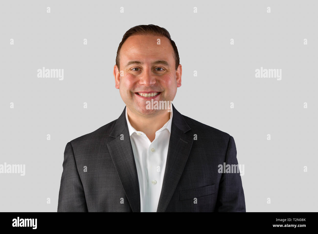 A portrait of a happy, smiling businessman in a black suit with a white background and copy space. Stock Photo