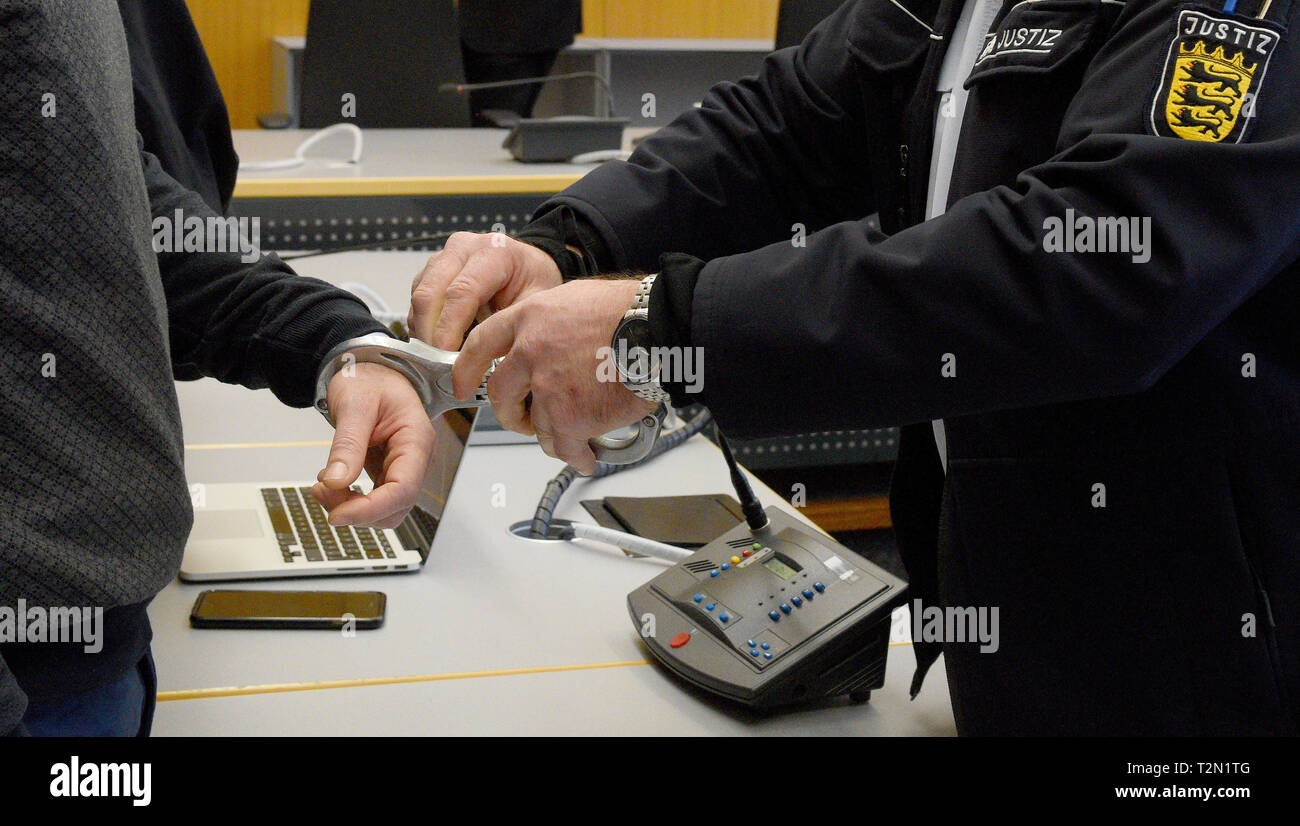 Ulm, Germany. 02nd Apr, 2019. In the district court, a judicial guard removes the handcuffs from the defendant. About two years after the murder of a young Albanian in Germany, the Ulm Regional Court announced the verdict. The accused, who is also of Albanian origin, is said to have played a central role in the murder of the victim, according to the public prosecutor's office. The motive was an archaic 'blood revenge' in the course of a feud between hostile families in Albania. The court sentenced the accused to life imprisonment for murder. Credit: Stefan Puchner/dpa/Alamy Live News Stock Photo