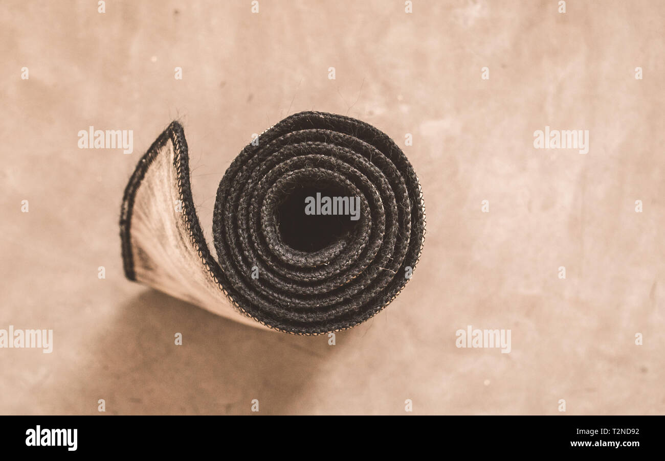 Rolled yoga mat after exercise isolated on rustic cement floor