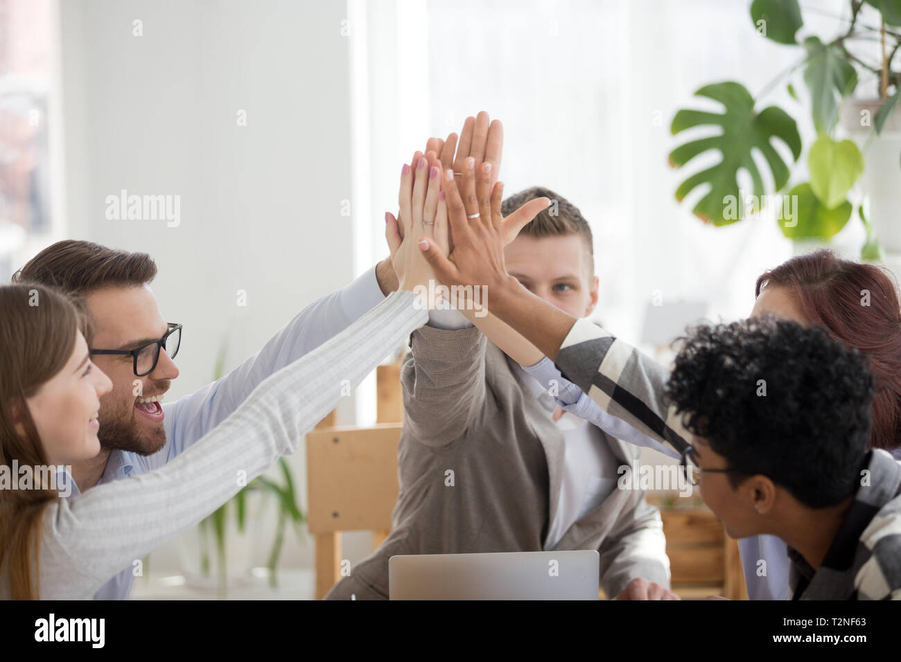Happy diverse businesspeople team giving high five sitting in office at ...
