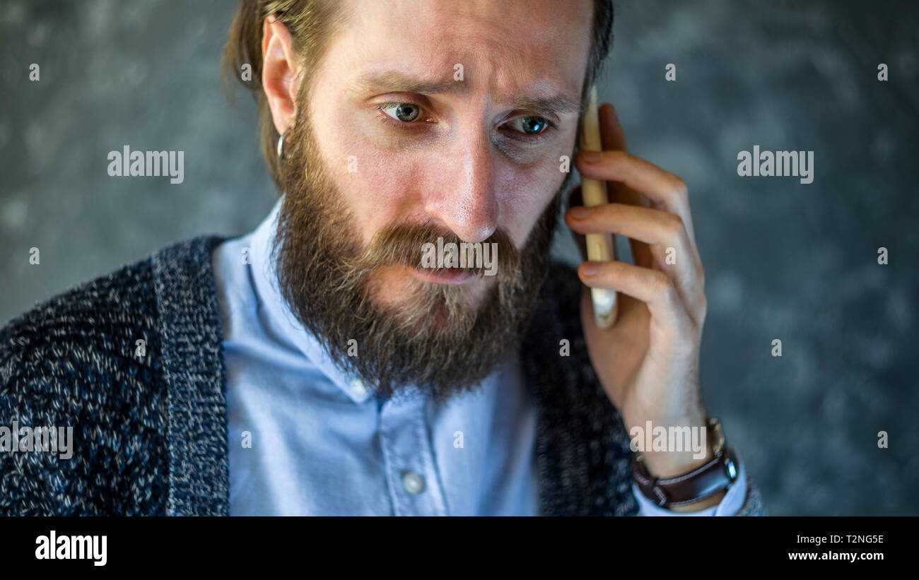 Distraught with Grief, a Bearded Man Who Received Bad News by Telephone. Unpleasant Conversation. Getting Bad News Concept Stock Photo